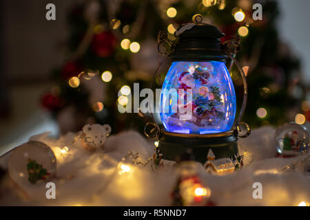 Decorazione di natale, snow dome, globo con decorazioni per la tavola, Santaclaus sulla slitta con il bambino in scena invernale, albero di natale con luci Foto Stock