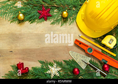 Casco di protezione, mason gli strumenti e le decorazioni di Natale su sfondo di legno Foto Stock