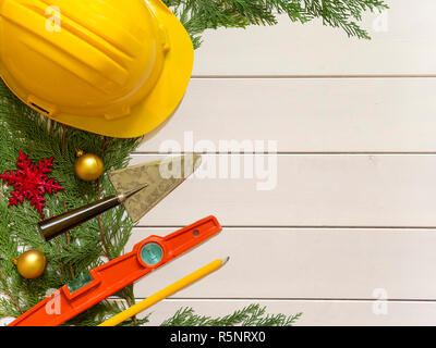 Casco di protezione, mason gli strumenti e le decorazioni di Natale in legno su sfondo bianco Foto Stock