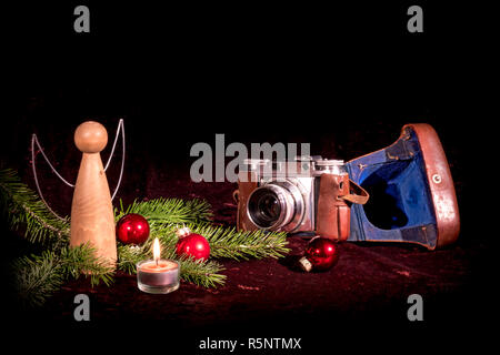 Angelo in legno e la vecchia macchina fotografica addobbate a festa con abeti e baubles Foto Stock