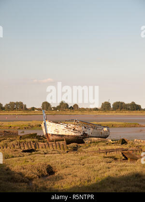 Moored vecchio arrugginito in legno bianco grande barca nella luce del sole a bordo del fiume acqua nera Maldon Foto Stock