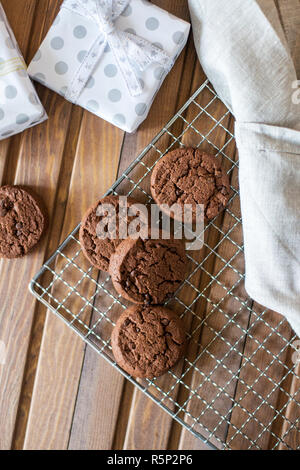 Biscotti al cioccolato a griglia in metallo, con tovagliolo e presentare riquadri vicino su uno sfondo di legno. Composizione di natale Foto Stock