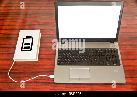 Prenota collegato a un computer portatile tramite un caricabatteria USB. Il simbolo della batteria indica il livello di carica. Foto Stock