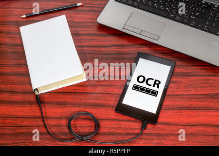 Prenota collegato ad una compressa attraverso un cavo USB su una scrivania. Riconoscimento ottico dei caratteri barra di caricamento. Foto Stock