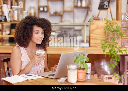 Femmina libero professionista che lavora in un negozio di caffè sul suo computer portatile Foto Stock