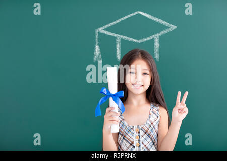 Ragazza nel tappo di graduazione in piedi prima di lavagna Foto Stock