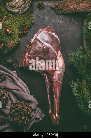 Raw gamba invecchiata di cervo con osso scuro sul tavolo da cucina sfondo , vista dall'alto. Carne cruda gamba di cervi. La cottura di preparazione di Arrosto di capriolo Foto Stock