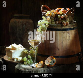 Di vino bianco con vino bianco e frutti su un tavolo di legno Foto Stock