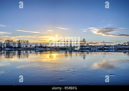 Vista dalla città di Zutphen, Paesi Bassi attraverso il lento fluire fiume IJssel verso la sponda opposta al tramonto in inverno Foto Stock