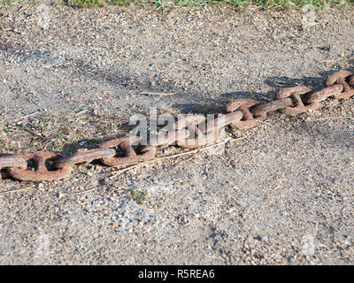 Il vecchio metallo arrugginito catena attraverso il pavimento di pietra al di fuori Foto Stock