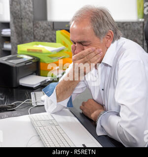 Senior uomo seduto disperatamente a una scrivania Foto Stock