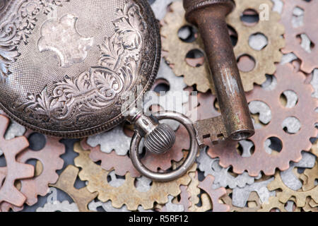 Panta Rhei concetto: antico orologio da tasca, vecchia chiave vintage e ora gli ingranaggi metallici sulla pietra naturale dello sfondo. Foto Stock