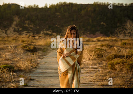Giovane e bella donna che cammina su un percorso di legno avvolto con un asciugamano di lana Foto Stock
