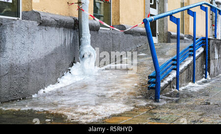 Acqua congelata nel tubo di scolo freddo pungente. In inverno il pericolo di caduta di ghiaccioli da tetti Foto Stock