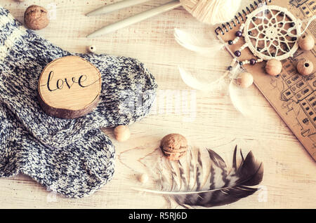 Composizione con l'iscrizione di amore, di legno e di elementi a maglia. Accogliente fotografia nello stile di un hugge. Foto Stock