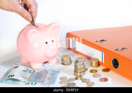 Mano inserire una moneta nell piggybank Foto Stock