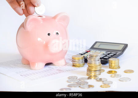 Mano inserire una moneta nell piggybank Foto Stock