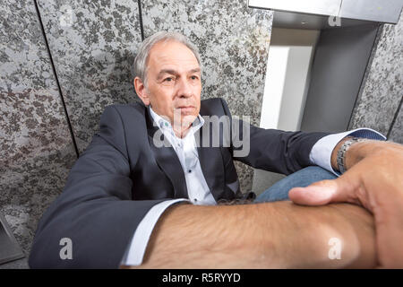 Senior uomo in tuta è disperatamente seduta sul pavimento Foto Stock