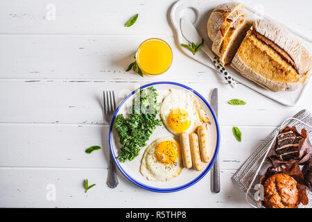 Ristorante e bar Colazione La colazione è servita con uova fritte, insalata, muffin e succo di arancia su bianco tavolo in legno, vista dall'alto, copia dello spazio. Foto Stock