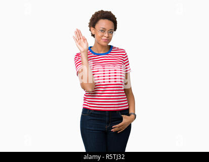 Bella giovane americano africano donna che indossa gli occhiali su sfondo isolato rinuncia a dire ciao felice e sorridente, gentile gesto di benvenuto Foto Stock