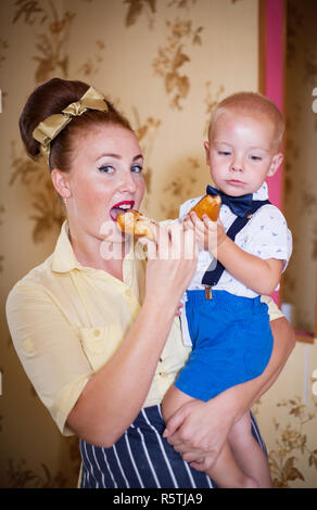 Madre e figlio in cucina con pasticcini. Studio shot, arredamento. Foto Stock