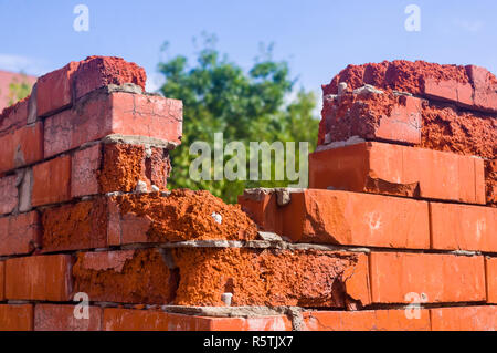 Weathered rovinato angolo del rosso parete di mattoni in una giornata di sole Foto Stock