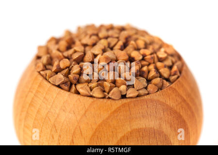 Arrosto di chicchi di grano saraceno in ciotola di legno isolato su sfondo bianco con percorso di clipping. Foto Stock