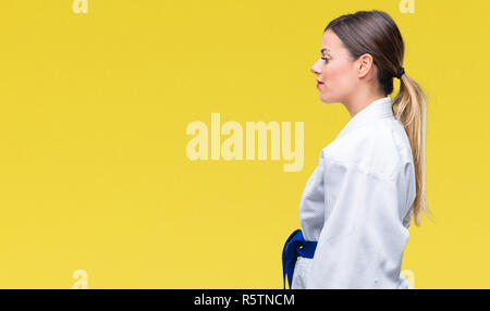 Giovane bella donna che indossa il karate kimono uniforme su sfondo isolato guardando al lato, profilo relax posano con faccia naturale con fiduciosa smil Foto Stock