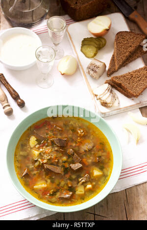 Rassolnik, tradizionale zuppa di Russo, servito con vari snack e la vodka. Stile rustico. Foto Stock