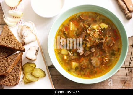 Rassolnik, tradizionale zuppa di Russo, servito con vari snack e la vodka. Stile rustico. Foto Stock