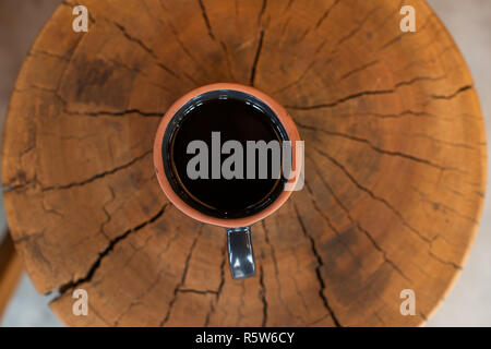 Tazza da caffè riempito di caffè nero, servita su una superficie di legno, vista dall'alto Foto Stock
