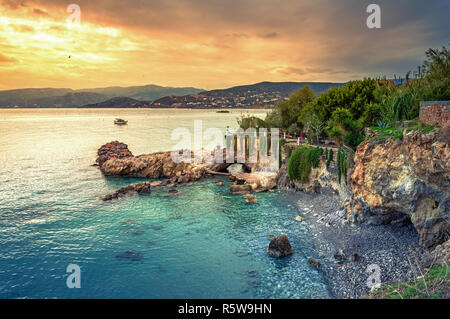 Scenic Votsalo spiaggia con grotte e una barca da pesca in Agios Nikolaos, Creta, Grecia Foto Stock