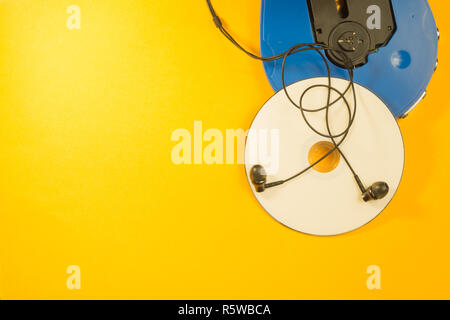 Cd e lettore compact disc con gli auricolari su sfondo giallo Foto Stock