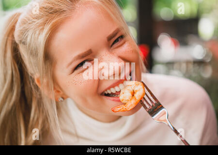 Giovane bella donna mangiare pasta nera con piatti a base di frutti di mare e nero di seppia nel ristorante all'aperto. Divertente e bello. Foto Stock