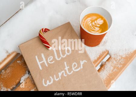Ciao inverno sfondo innevato, natale candi canne, tazza di caffè, libro d'inverno. Foto Stock