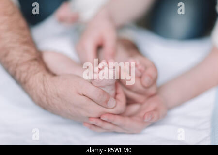 Bambini I piedi nelle mani dei genitori Foto Stock