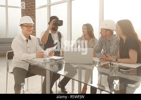 Equipaggio di giovani designer professionisti a discutere le idee circa il blueprint durante il tavolo riunioni in studio moderno Foto Stock