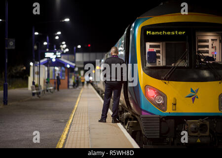La protezione / conduttore di un primo Transpennine express treno di effettuare dei controlli di sicurezza prima di spedire il suo treno a Chorley. Foto Stock