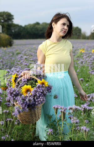 Giovane donna in un viola di campo dei fiori Foto Stock