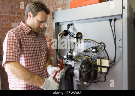 Plumber riparazione di una caldaia a condensazione nella sala caldaie Foto Stock