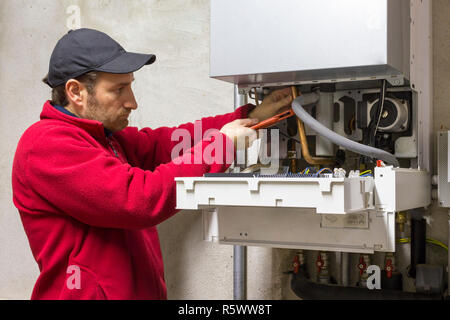 Plumber riparazione di una caldaia a condensazione Foto Stock