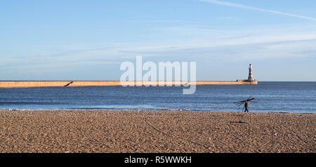 Uomo che porta driftwood, Roker beach, Sunderland, England, Regno Unito Foto Stock