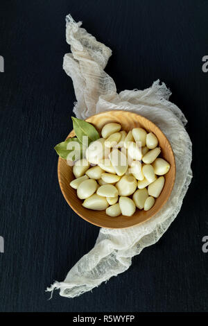 Aglio fresco teste, set di chiodi di garofano in piastra su una pietra nera superficie, vista dall'alto, copiare lo spazio, lo spazio libero per il testo. Foto Stock