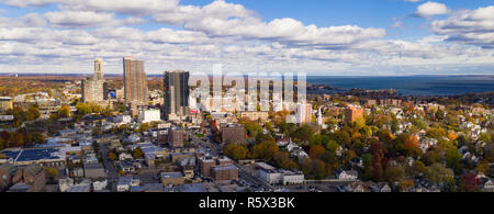 Il sole fa capolino tra le nuvole di colpire e illuminando il nucleo urbano di New Rochelle New York Foto Stock