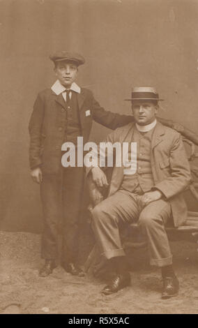 * L'ANNATA 1908 Edwardian Cartolina fotografica di un padre e figlio in uno studio fotografico a Skegness, Lincolnshire. Foto Stock