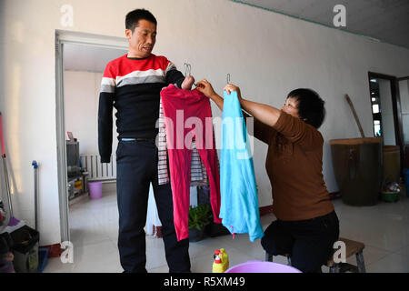 (181203) -- HOHHOT, Dicembre 3, 2018 (Xinhua) -- Liu Hai (L) si prepara per asciugare i panni puliti da sua moglie Li Meiwen a casa nella città Kouhezi, Kulun Banner del nord della Cina di Mongolia Interna Regione Autonoma, dal 1 dicembre 2018. Liu Hai, un soldato in pensione che ha perso le sue braccia in un incidente di lavoro nel 1997, e li Meiwen, che ha perso le sue gambe quando aveva tredici anni, sono state nel matrimonio per undici anni attraverso l aiuto reciproco nella vita. Dopo conoscere Li Meiwen sulla TV in 2007, Liu hai messo in contatto con lei. Due mesi più tardi, Li è andato alla Mongolia interna per la prima volta. Sebbene ricevere aiuto da parte di parenti e amici Foto Stock