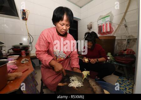 (181203) -- HOHHOT, Dicembre 3, 2018 (Xinhua) -- Li Meiwen (anteriore) si prepara per la cena a casa nella città Kouhezi, Kulun Banner del nord della Cina di Mongolia Interna Regione Autonoma, nov. 30, 2018. Liu Hai, un soldato in pensione che ha perso le sue braccia in un incidente di lavoro nel 1997, e li Meiwen, che ha perso le sue gambe quando aveva tredici anni, sono state nel matrimonio per undici anni attraverso l aiuto reciproco nella vita. Dopo conoscere Li Meiwen sulla TV in 2007, Liu hai messo in contatto con lei. Due mesi più tardi, Li è andato alla Mongolia interna per la prima volta. Sebbene ricevere aiuto da parte di parenti e amici, il giovane ancora provare a l Foto Stock