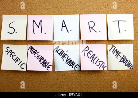 Un bigliettino giallo iscritto, didascalia, iscrizione frase SMART in nero ext su un foglietto adesivo imperniato ad un tappo di sughero bacheca specifici, misurabili, raggiungibili, registrati, tempestiva colorato sticky notes sul sughero bulletin board Foto Stock