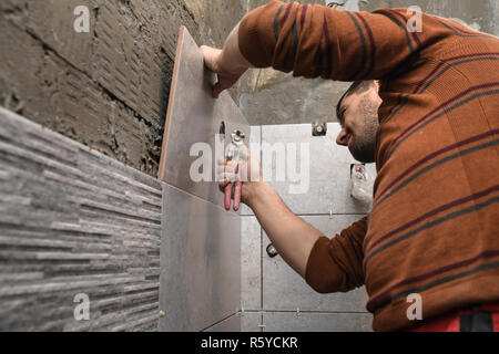 Il taglio di piastrelle di ceramica manualy. Apertura di un foro nella piastrella. Foto Stock