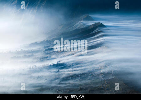 La nebbia che fluisce oltre Cemoro Lawang Foto Stock